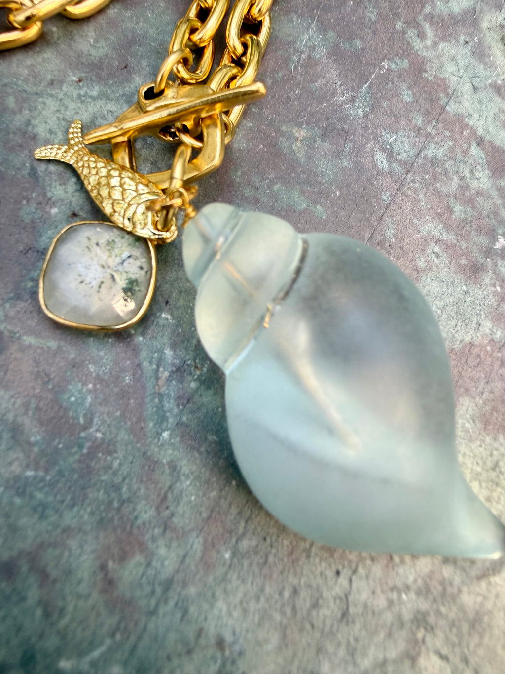 pale blue, acrylic shell with gold fish and agate charm on gold link chain, front toggle closure